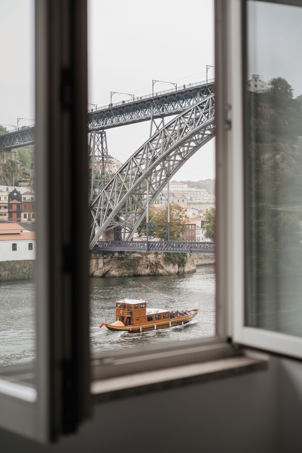 Vista a través de una ventana: un río, un puente y una embarcación.