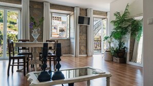 A dining area with a table and chairs, a decorative vase, and a large window with a view of buildings. - Red House by the River (Porto)