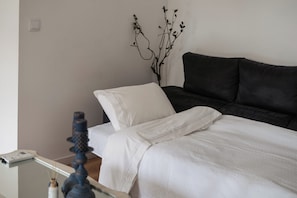 Une chambre à coucher avec un lit, une table de chevet, une lampe et une plante fixée au mur.