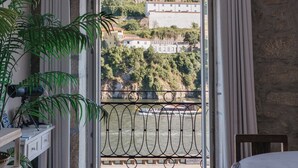 A balcony with a view of a hillside and a body of water. - Red House by the River (Porto)