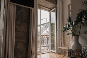 Une pièce dotée d’une grande porte vitrée donnant sur un balcon, d’une plante en pot, d’une chaise blanche et d’un vase décoratif.
