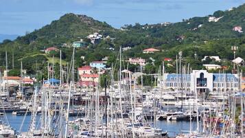 Un port de plaisance où sont amarrés de nombreux voiliers, entouré de bâtiments et avec des collines en arrière-plan.