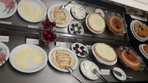 A display case with various desserts including cakes, pies, and fruit. - Buriti Hotel (Jatai)
