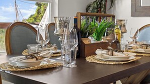 A dining table set with clear glassware, plates, and a wooden centerpiece. - Lake Travis Premium - Austin Views with Great Reviews (Austin)