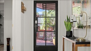 A black-framed door with a view of a wooden deck and a lattice fence. - Lake Travis Premium - Austin Views with Great Reviews (Austin)