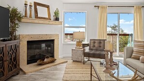 A living room with a fireplace, a television, a sofa, and a view of the outdoors. - Lake Travis Premium - Austin Views with Great Reviews (Austin)