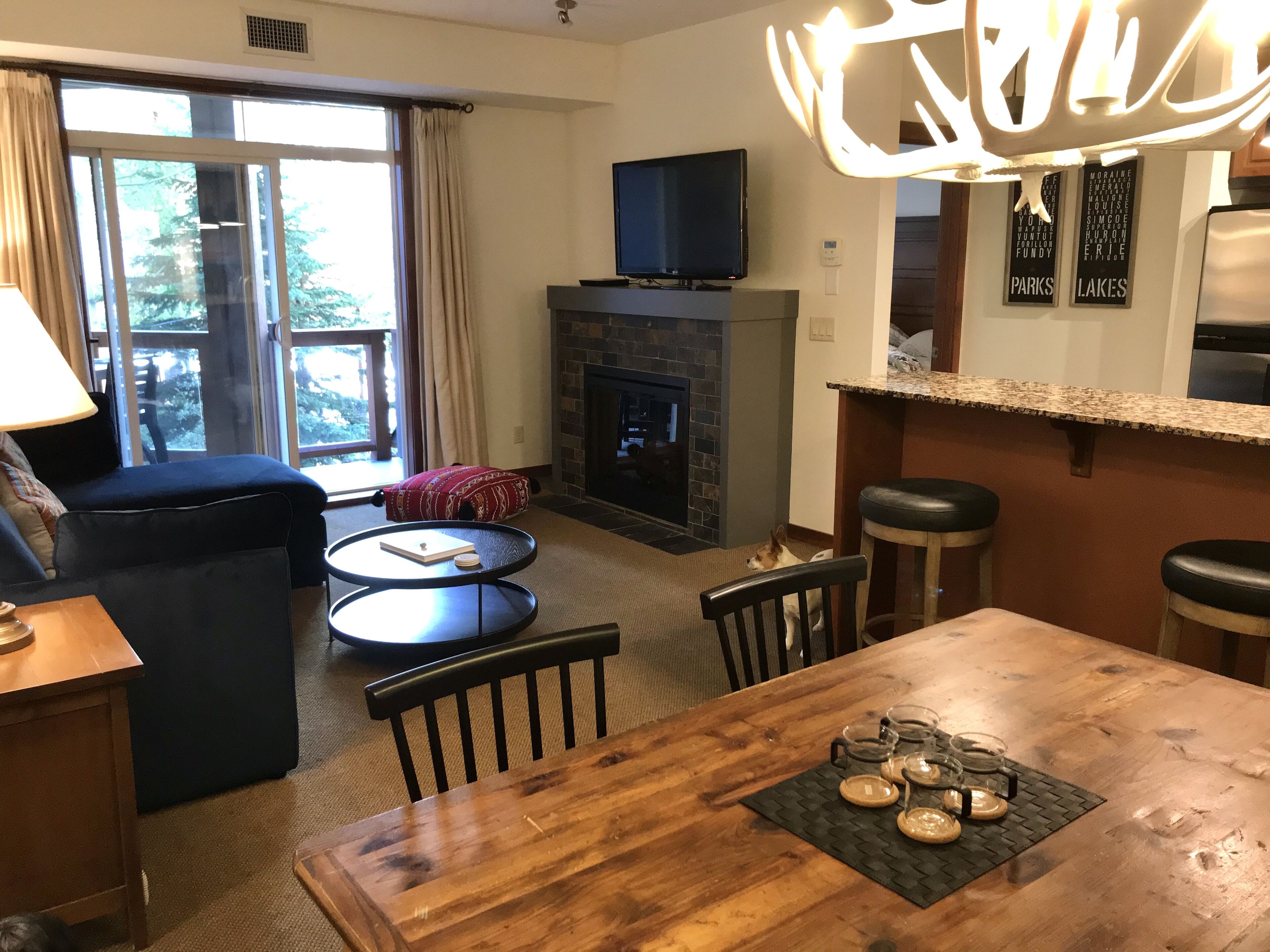 A cozy living room with a fireplace, a television, and a dining area with a table set for four.
