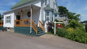 A two-story house with a porch, a staircase, and a sign indicating a restaurant. - La Casa en Shediac (Shediac)