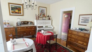 A dining area with a red tablecloth, wooden chairs, a chandelier, and a piano. - La Casa en Shediac (Shediac)