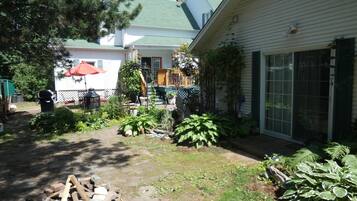 Un jardin arrière aménagé avec un foyer en pierre, des plantes en pot et une terrasse en bois.
