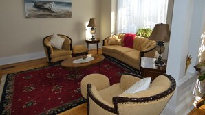 A living room with a sofa, two armchairs, a coffee table, and a painting of a boat on the wall. - La Casa en Shediac (Shediac)