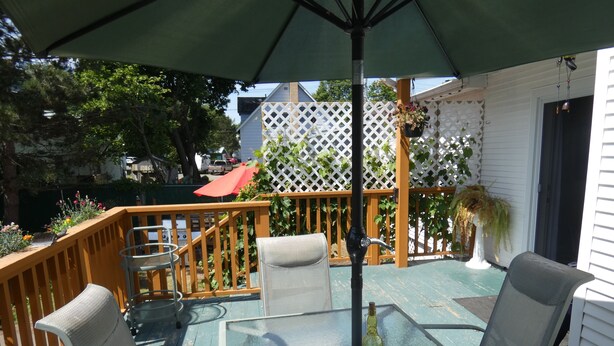 An outdoor patio with a glass table, metal chairs, and a wooden deck. - La Casa en Shediac (Shediac)