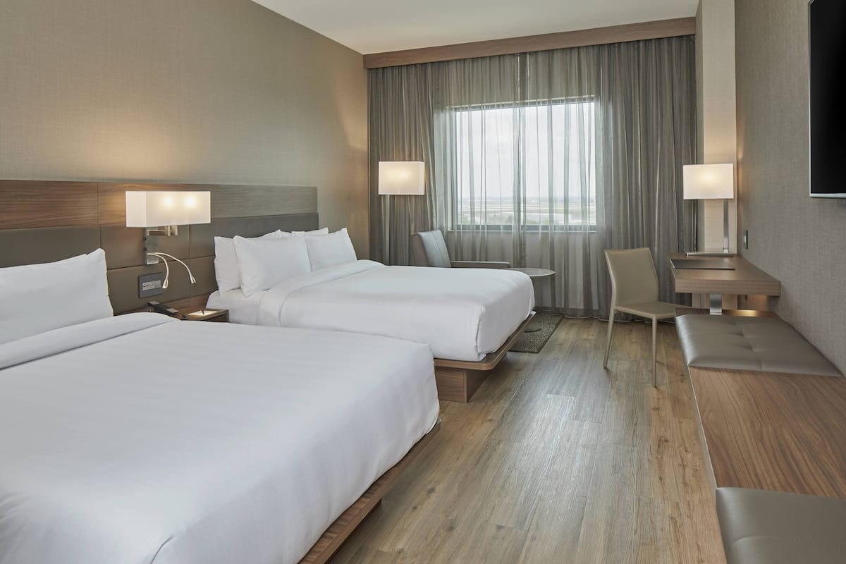 Een hotelkamer met twee bedden, een bureau, een stoel en een televisie.