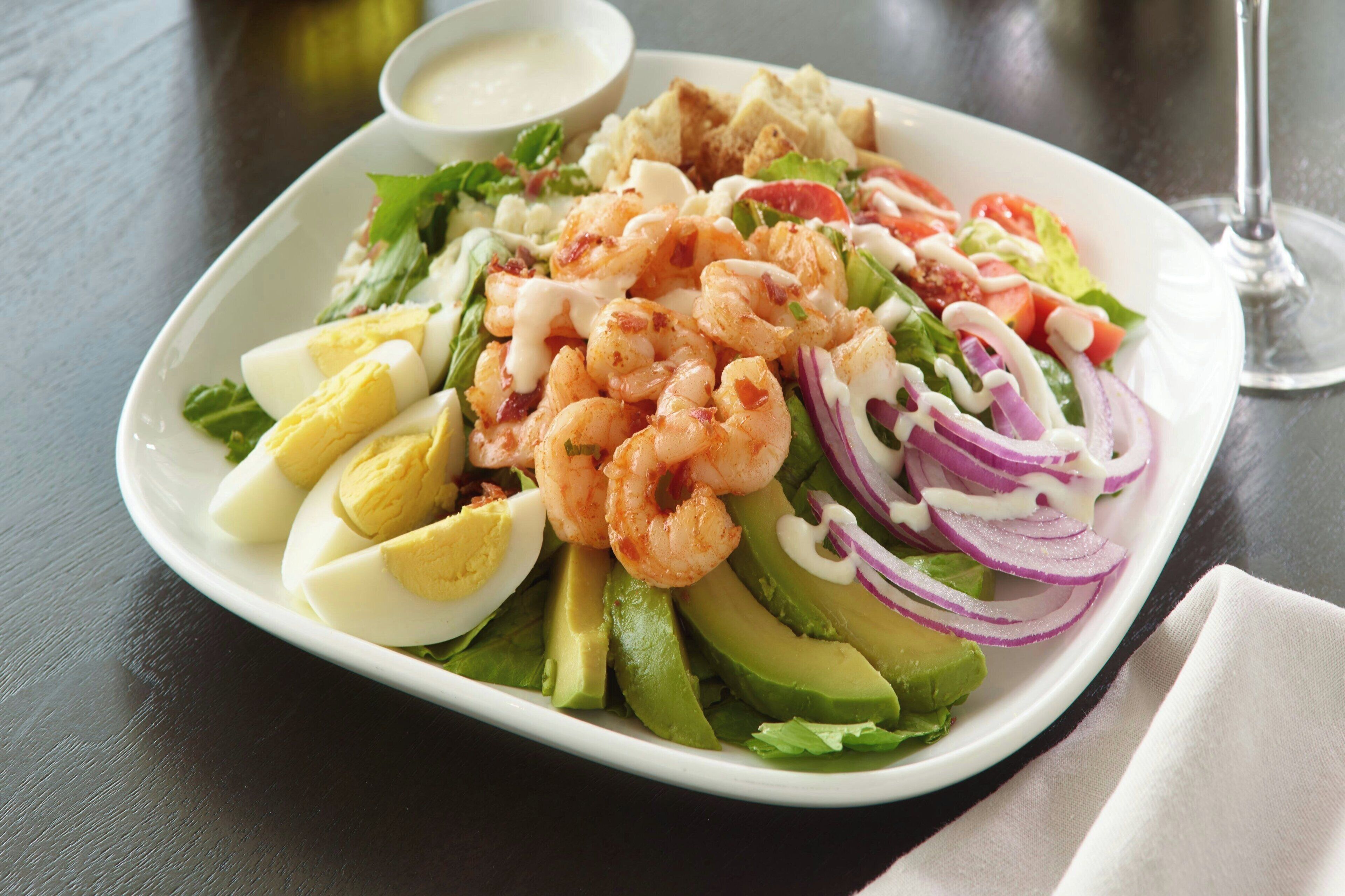 A plate of shrimp, avocado, and eggs on a table.