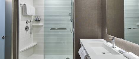 A modern bathroom with a glass-enclosed shower, a white sink, and a large mirror.