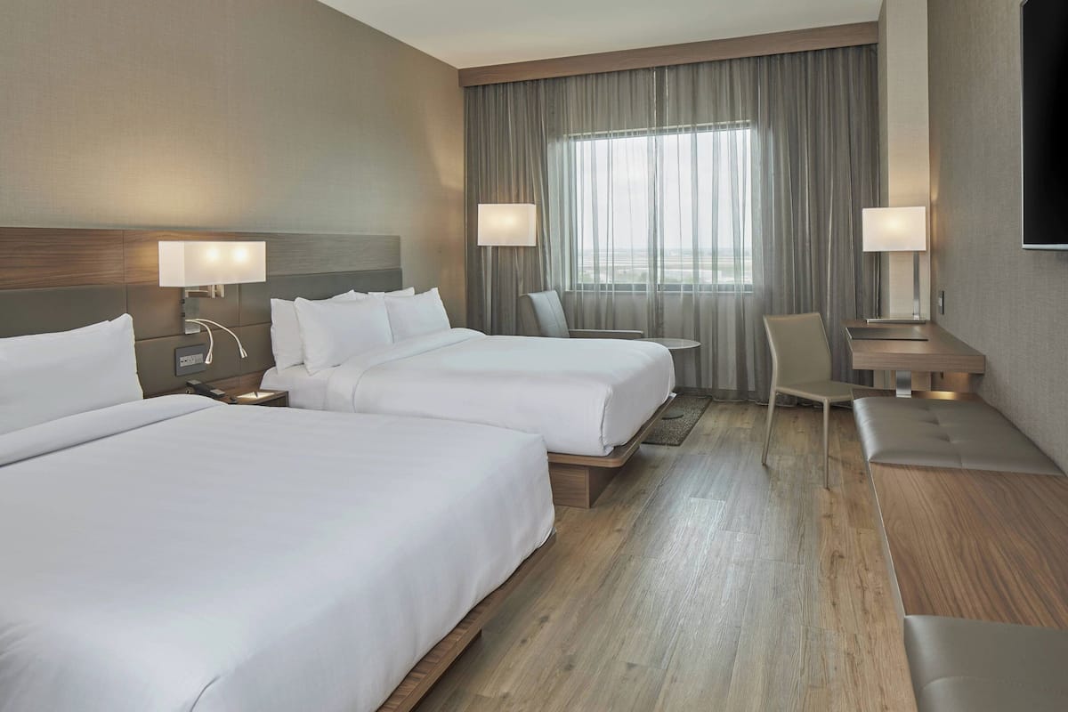Een hotelkamer met twee bedden, een bureau, een stoel en een televisie.