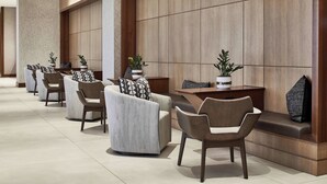 Un hall d’entrée moderne, avec une rangée de canapés et de fauteuils, un comptoir d’accueil et des plantes en pot.