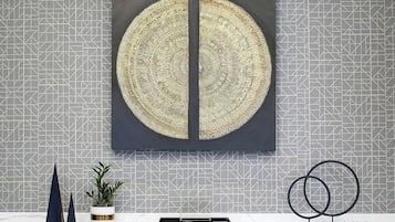 Ein modernes Interieur mit einer Wand mit geometrischem Muster, einem großen runden Kunstwerk und Dekorationen auf einer Theke.