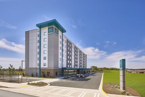 A modern hotel with a central atrium, multiple floors, and a parking area.