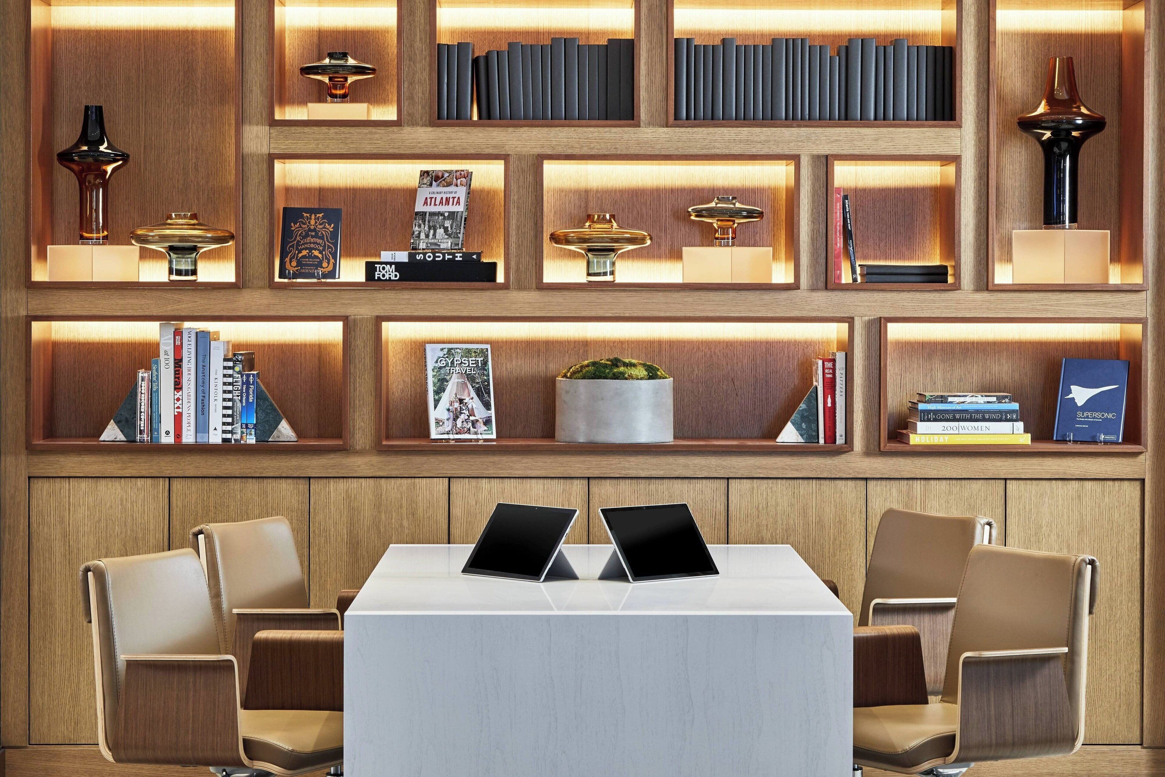 A modern library with bookshelves, decorative items, and a table with two laptops.