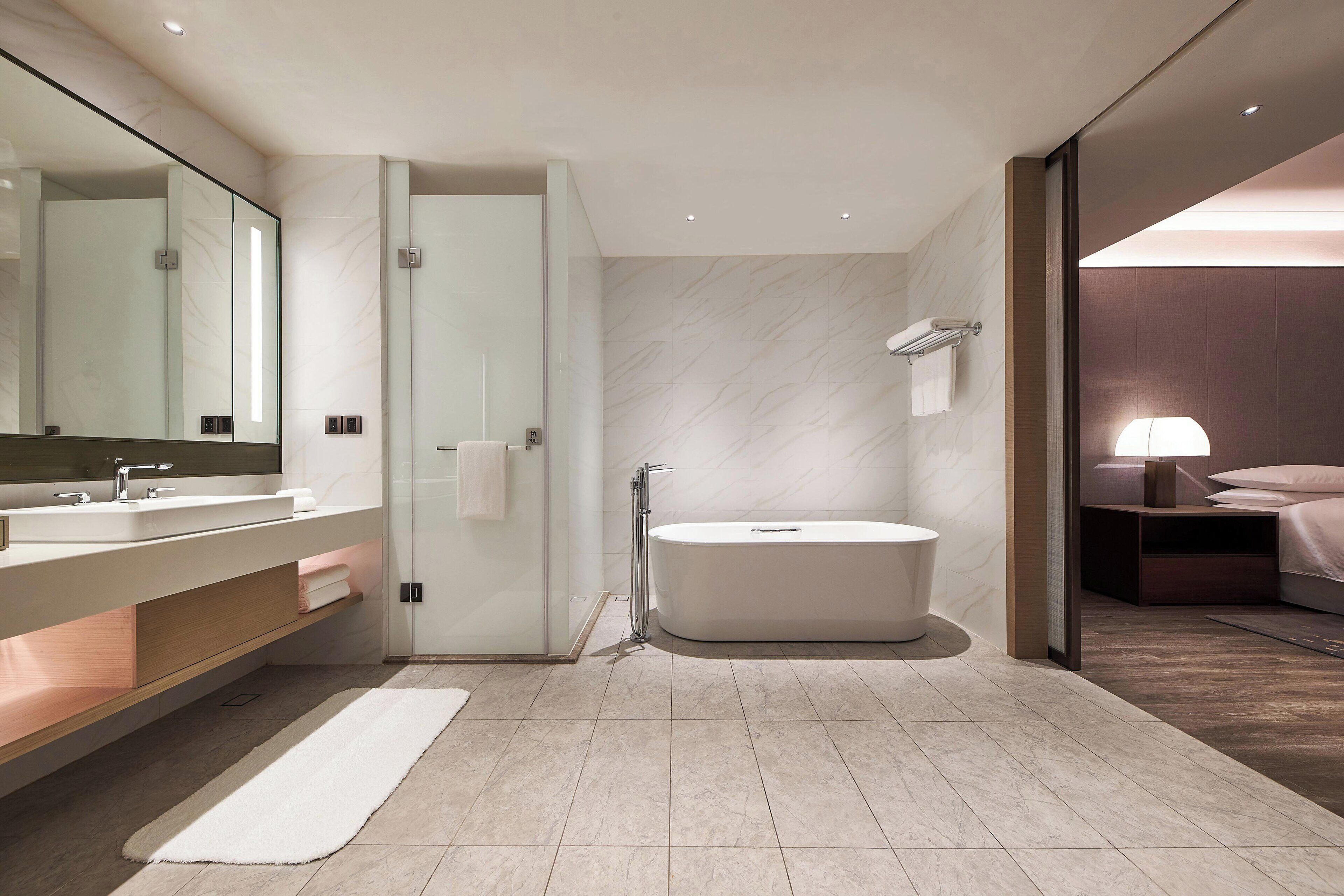 A modern bathroom with a large mirror, a bathtub, and a vanity with a sink.