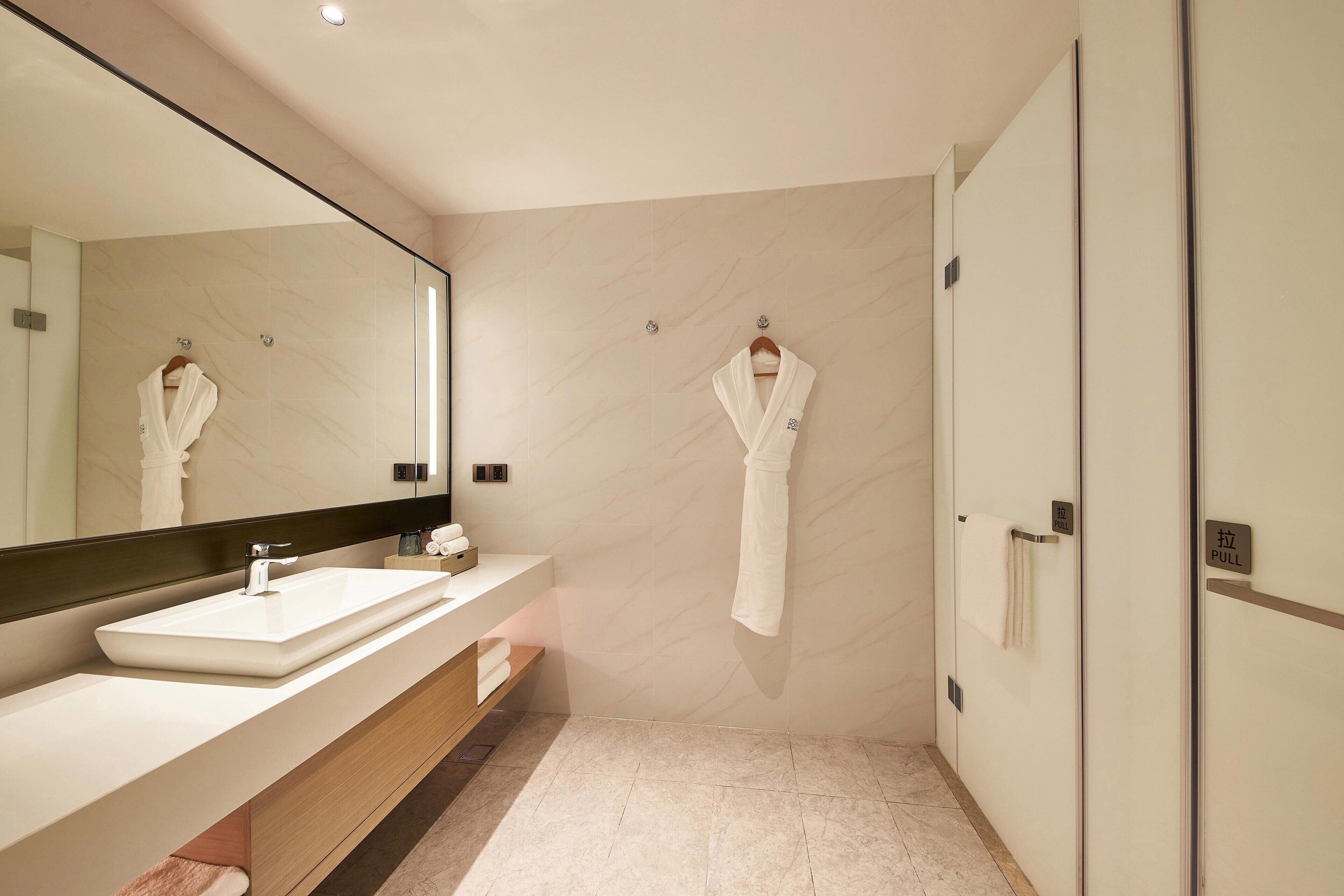 Un baño moderno con un espejo grande, un lavabo blanco y un perchero para toallas.