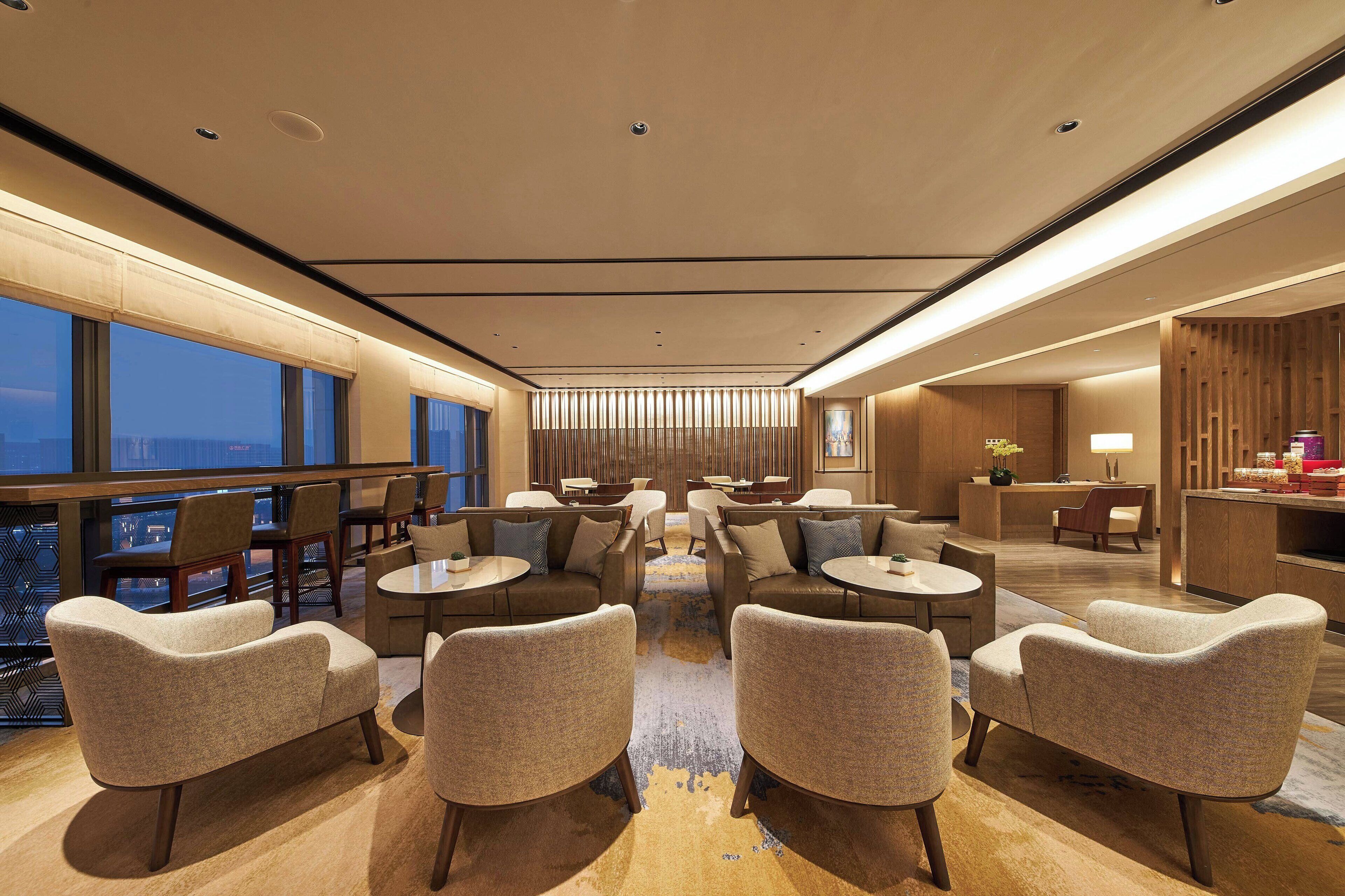 A modern hotel lobby with round tables, sofas, and a reception desk.
