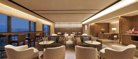 A modern hotel lobby with round tables, sofas, and a reception desk.