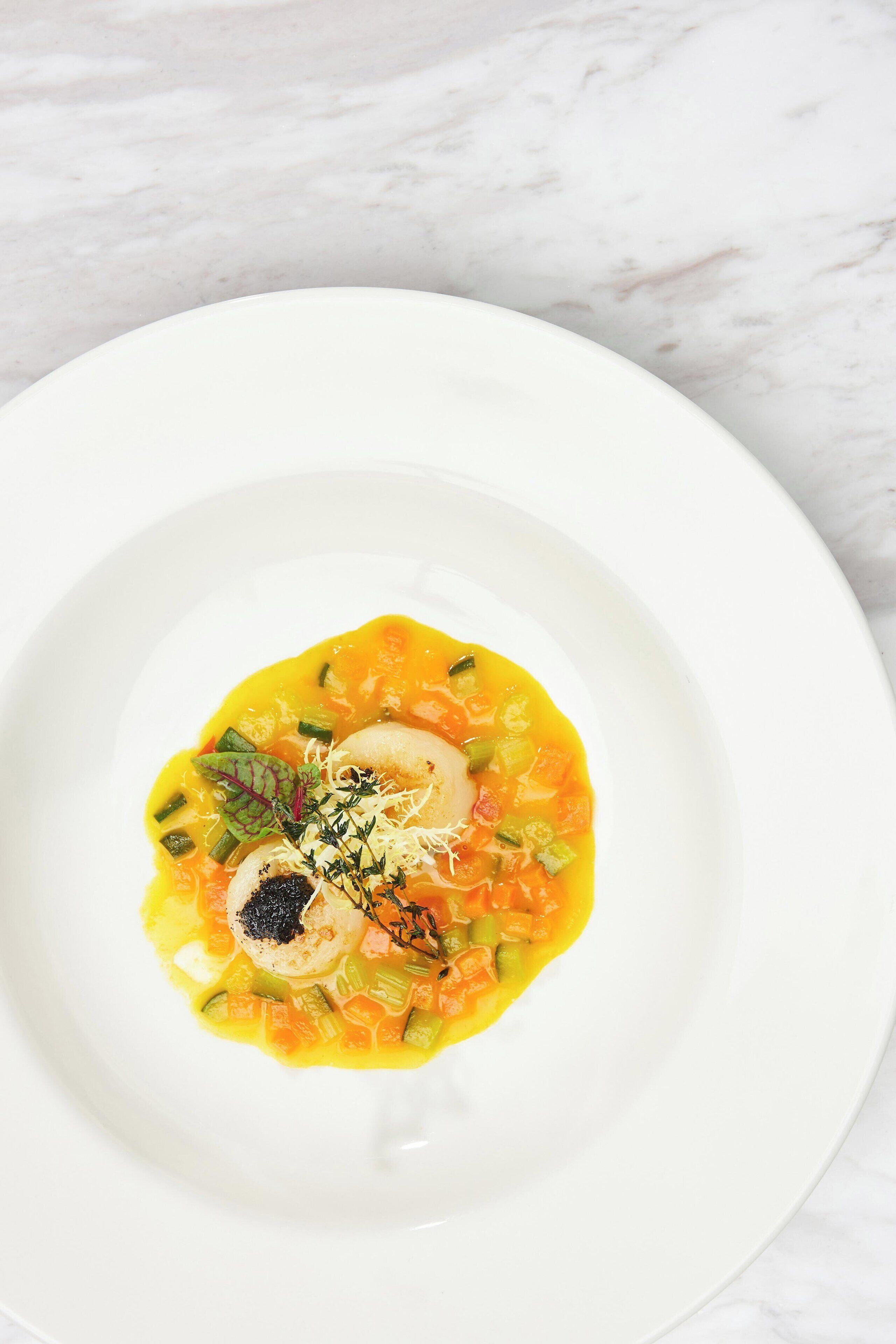 Un plato blanco con un plato colorido sobre una superficie de mármol.