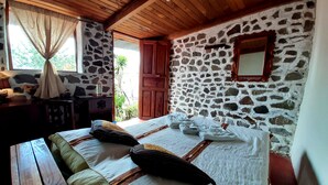 Een slaapkamer met een stenen muur, houten plafond en een bed met kussens.