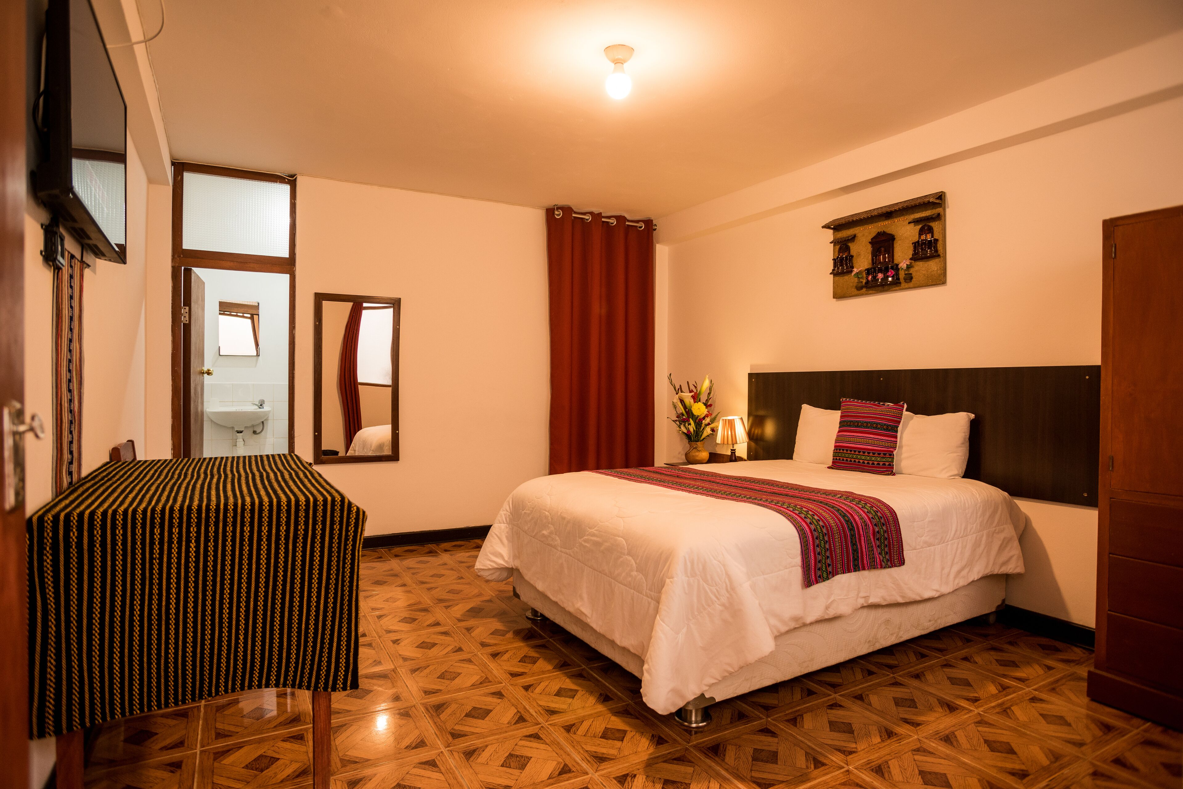 A hotel room with a bed, a table, and a mirror.