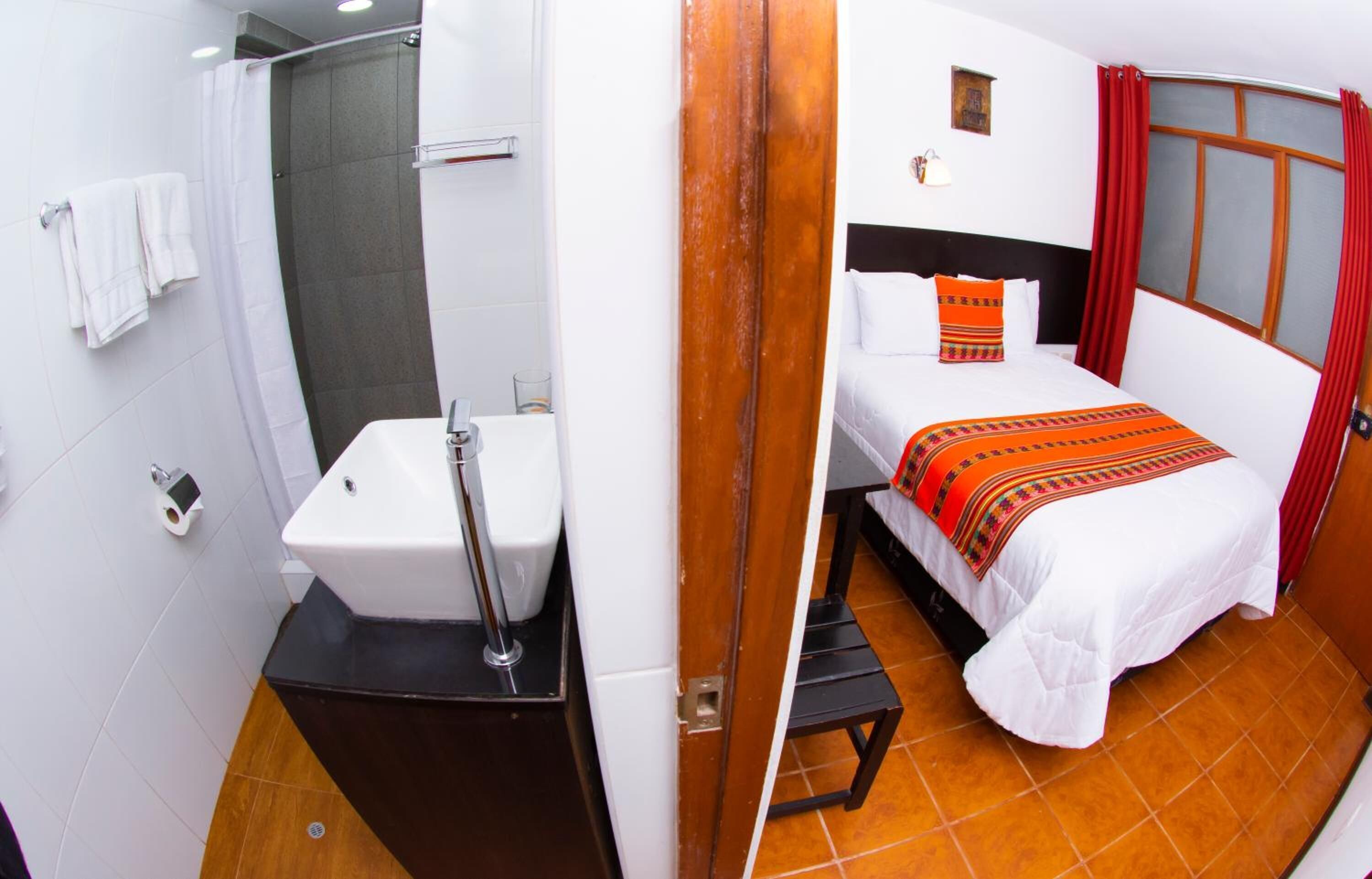 A hotel room with a shower, toilet, sink, bed, and a window with curtains.