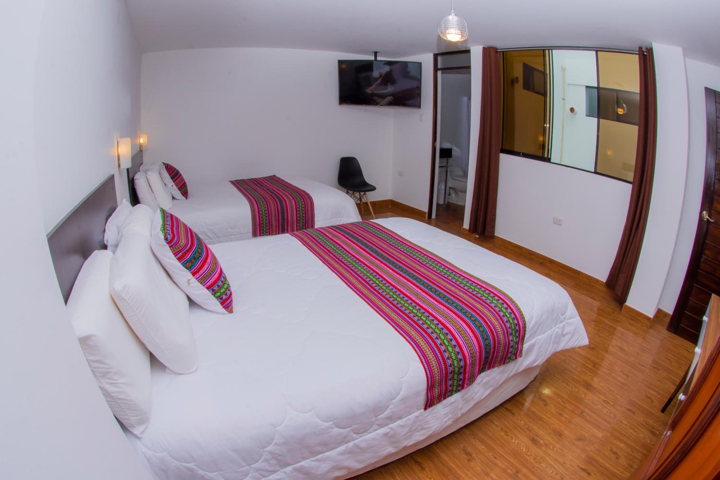 Een slaapkamer met twee bedden, een aan de muur bevestigde televisie en een schuifdeur naar een balkon.