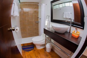 Un baño moderno con ducha, inodoro, lavabo y un espejo grande.