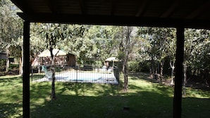 Un espacio al aire libre techado con piscina, rodeado de árboles y una valla.
