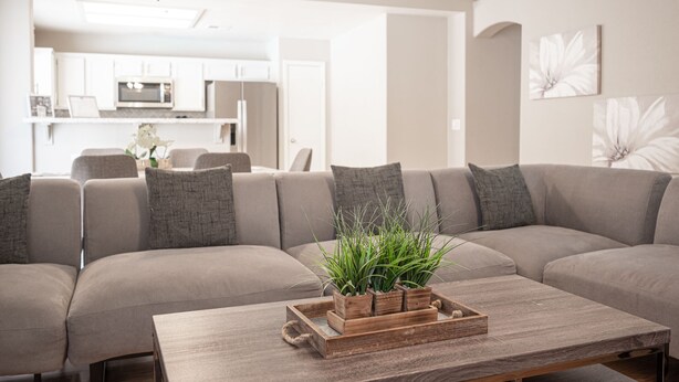 Una sala de estar moderna con un sofá modular, una mesa de centro de madera con una planta y un ventilador de techo.