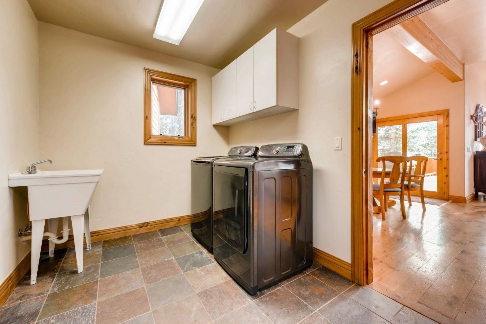 A laundry room with a washing machine, a sink, and a window.