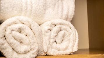 A wooden shelf with two rolled white towels.