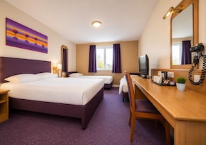 A hotel room with a bed, two bedside tables, a desk with a chair, a television, a coffee maker, and a window with curtains. - Stables Inn Aintree (Liverpool)