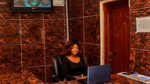 A reception desk with a laptop, a clock, and a door. - D'ISLAND hotel (Lekki)
