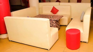 A modern living room with white sofas, a patterned coffee table, and red accents. - D'ISLAND hotel (Lekki)