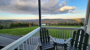 A porch with Adirondack chairs overlooking a scenic view of mountains and a lake. - Mountain Lodge 1st Floor - Ski-in/Out - Mtn View - Pvt Parking (Snowshoe)