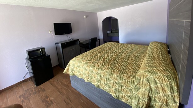 A bedroom with a bed, a desk, a television, and a microwave. - The Village Inn (Denham Springs)