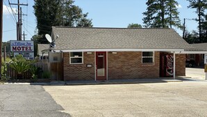 A brick motel with a red door, a satellite dish, and a Coca-Cola vending machine. - The Village Inn (Denham Springs)