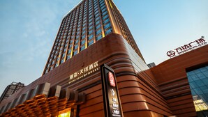 A tall hotel building with a modern design, featuring a prominent sign for the Wanda Plaza. - Li Cai Tian Qi Hotel Xianyang (Xianyang)
