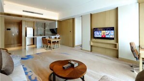 A modern hotel room with a living area, a dining space, and a TV mounted on the wall. - Li Cai Tian Qi Hotel Xianyang (Xianyang)