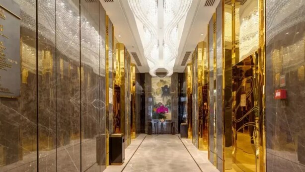 A luxurious hallway with marble walls, a central chandelier, and a floral arrangement at the end. - Li Cai Tian Qi Hotel Xianyang (Xianyang)