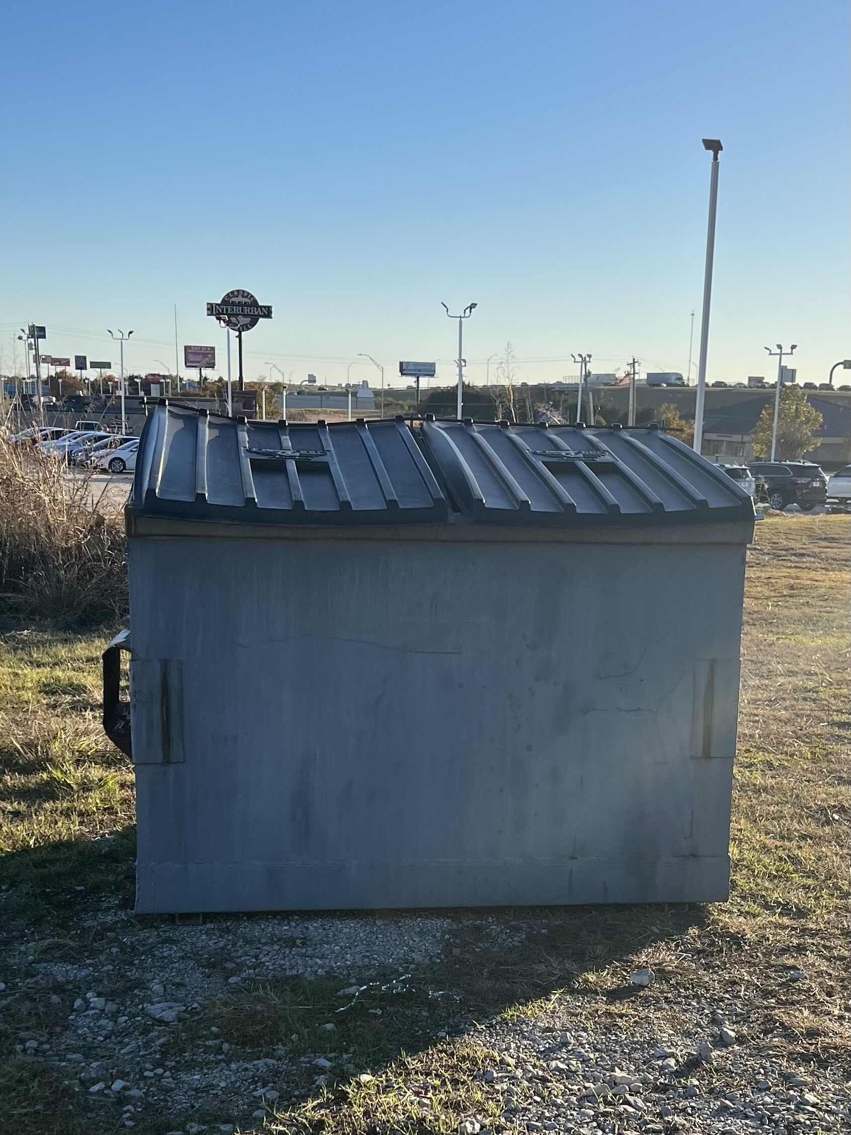 A large, rectangular metal structure with a sloped roof, situated in an open area with a clear sky.
