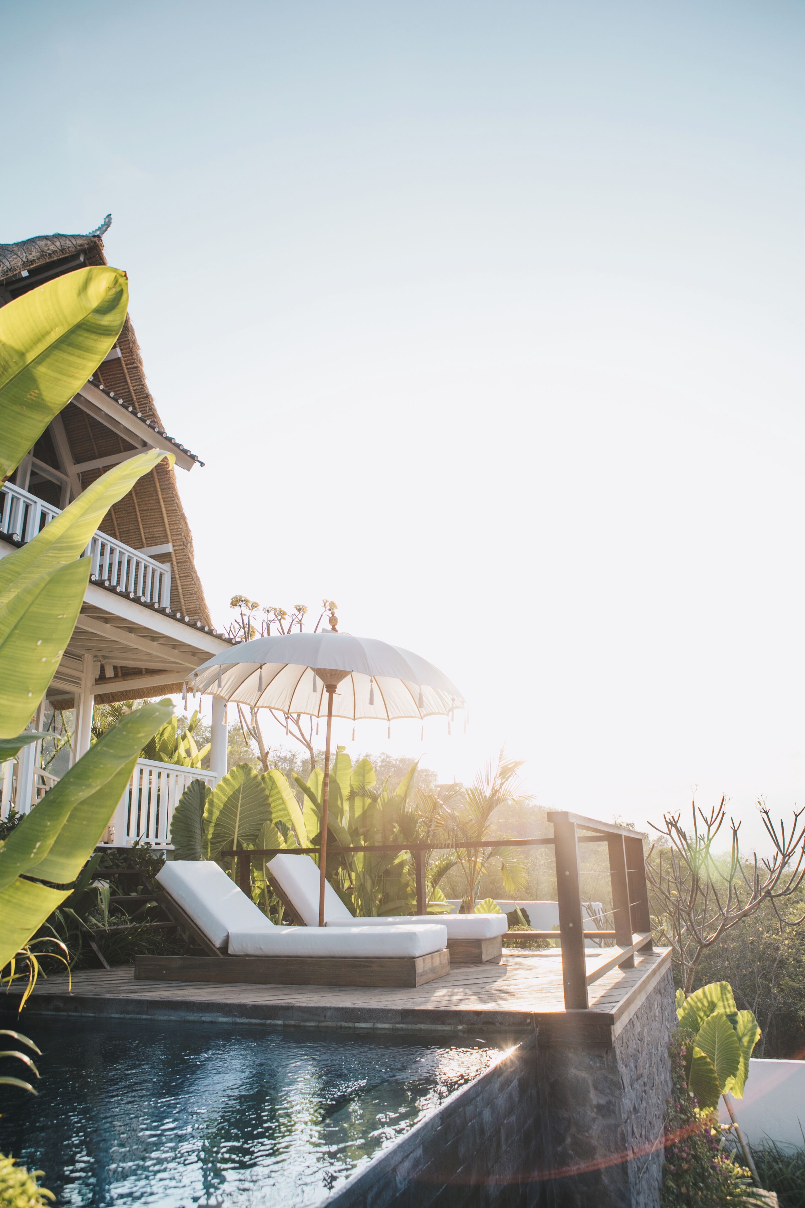 Ein Poolbereich mit Liegestühlen, einer Pergola und einem Gebäude mit Balkon.