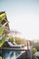Ein Poolbereich mit Liegestühlen, einer Pergola und einem Gebäude mit Balkon.